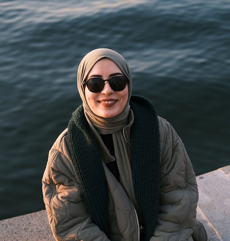 A woman sitting on a ledge next to a body of water